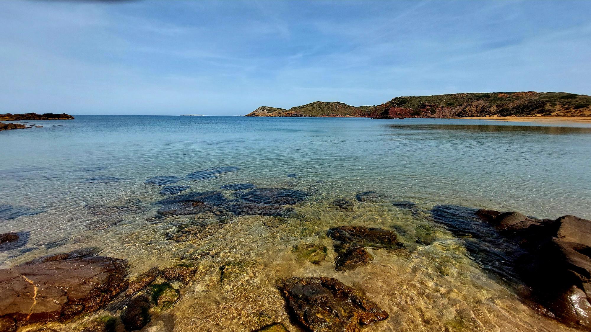 Turquoise water and rocky coastline at one of the best beaches in Menorca